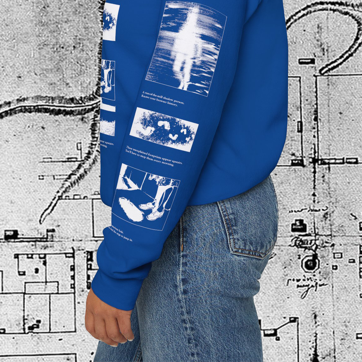 Grant Us Night Horror House blue sweatshirt sleeve with white graphic design text and a haunted house with ghosts and footprints and cursed objects and illustrations on a textured background