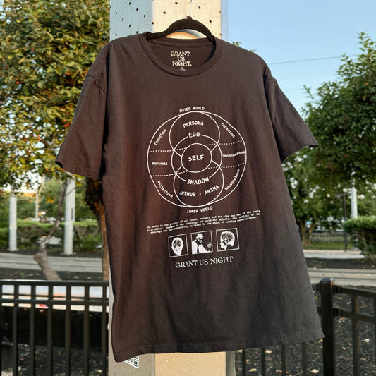 Grant Us Night Jungian Psyche black shirt with gray text and graphic design of figures and diagrams and chart and brain, on a hanger outdoors