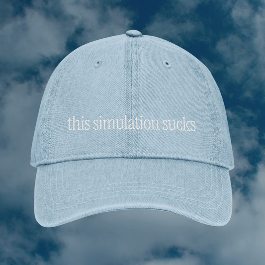 Grant Us Night Simulation light blue denim cap with 'this simulation sucks' white text embroidered against a blue sky background