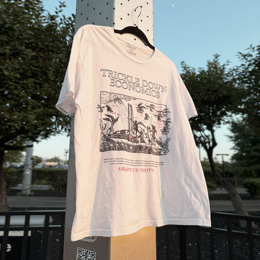 Grant Us Night Trickle Down white t-shirt with 'Trickle Down Economics' graphic design etching on a historical guillotine painting background on a hanger outdoors