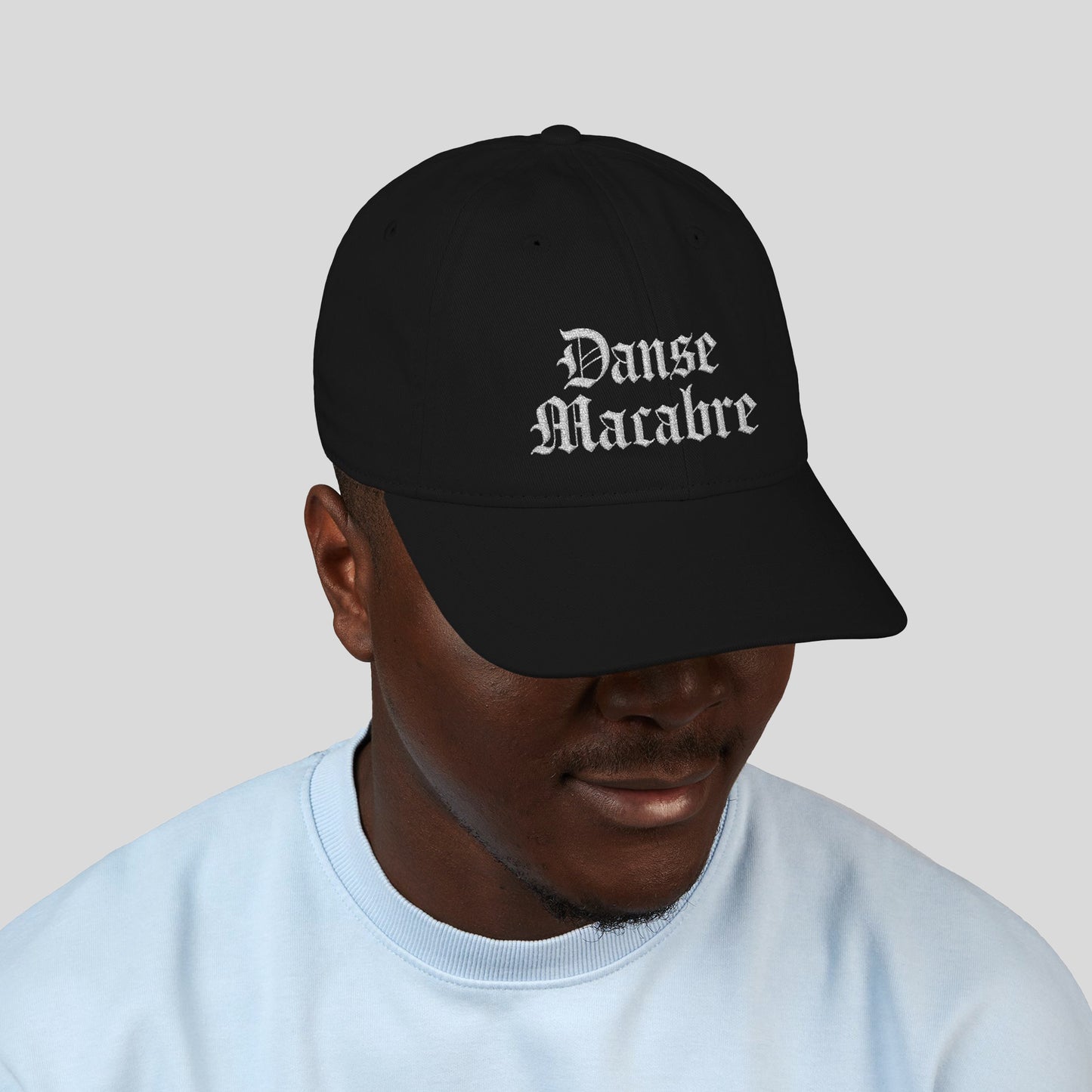 Person wearing Grant Us Night black cap with white embroidered 'Danse Macabre' text