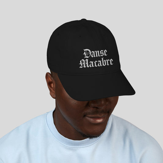 Person wearing Grant Us Night black cap with white embroidered 'Danse Macabre' text