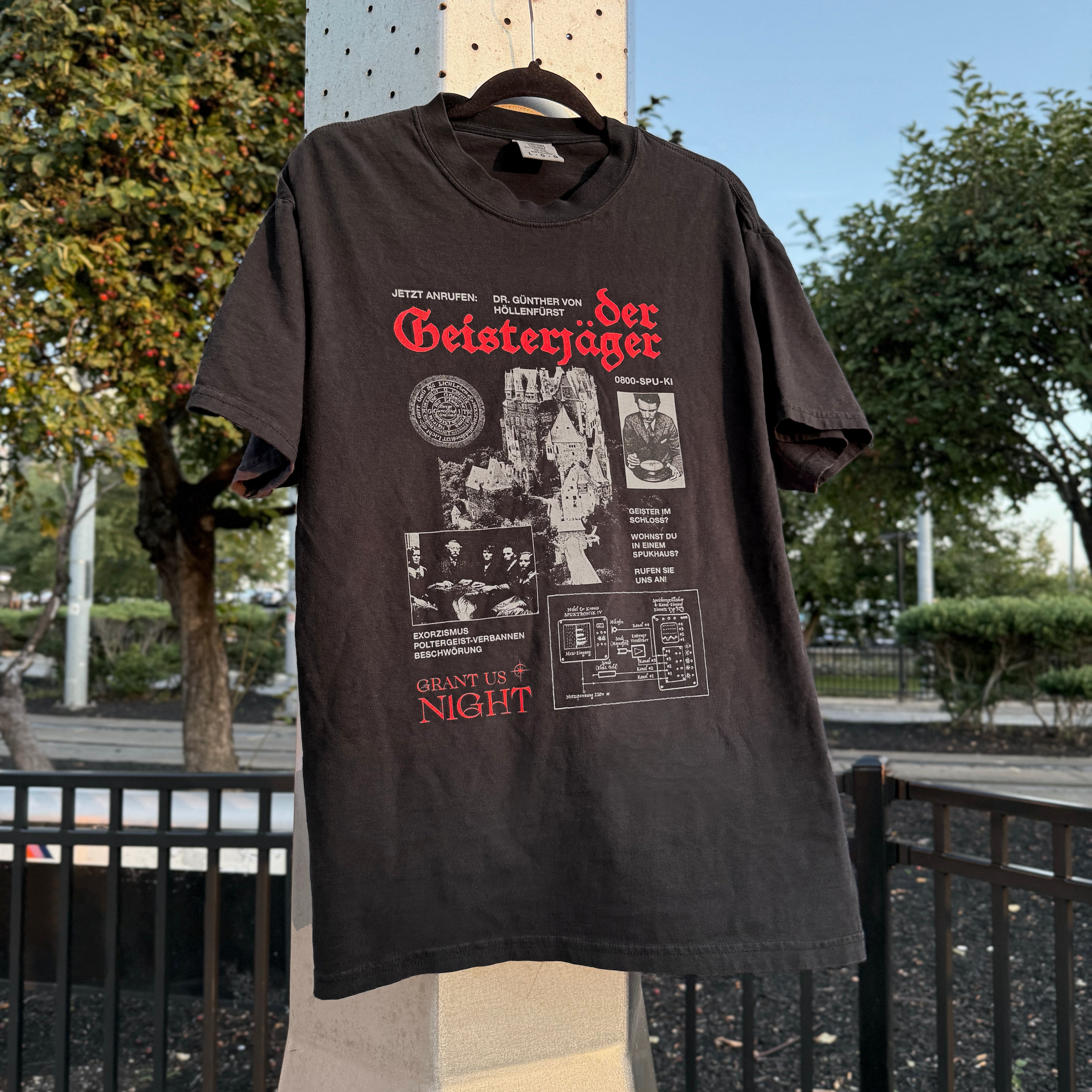 Grant Us Night Geisterjager black t-shirt with castle imagery and old photography and graphic design and German text on a blurred castle background hanging outdoors