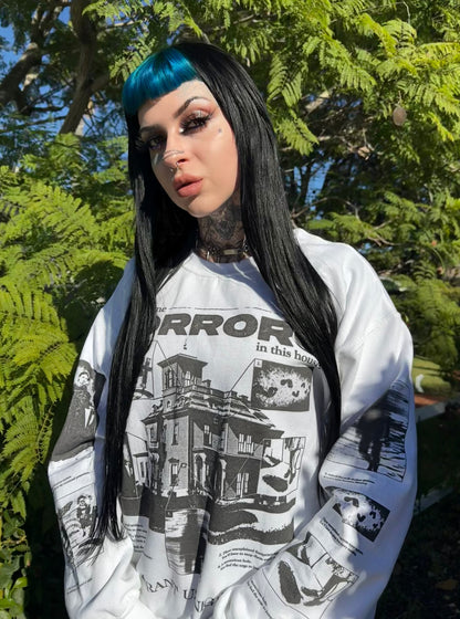 Person wearing a white Grant Us Night sweatshirt with black graphic design outdoors