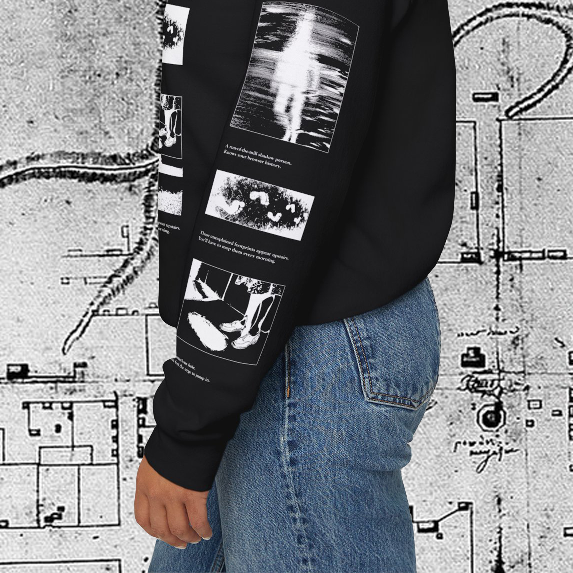 Grant Us Night Horror House black sweatshirt sleeve with white graphic design text and a haunted house with ghosts and footprints and cursed objects and illustrations on a textured background