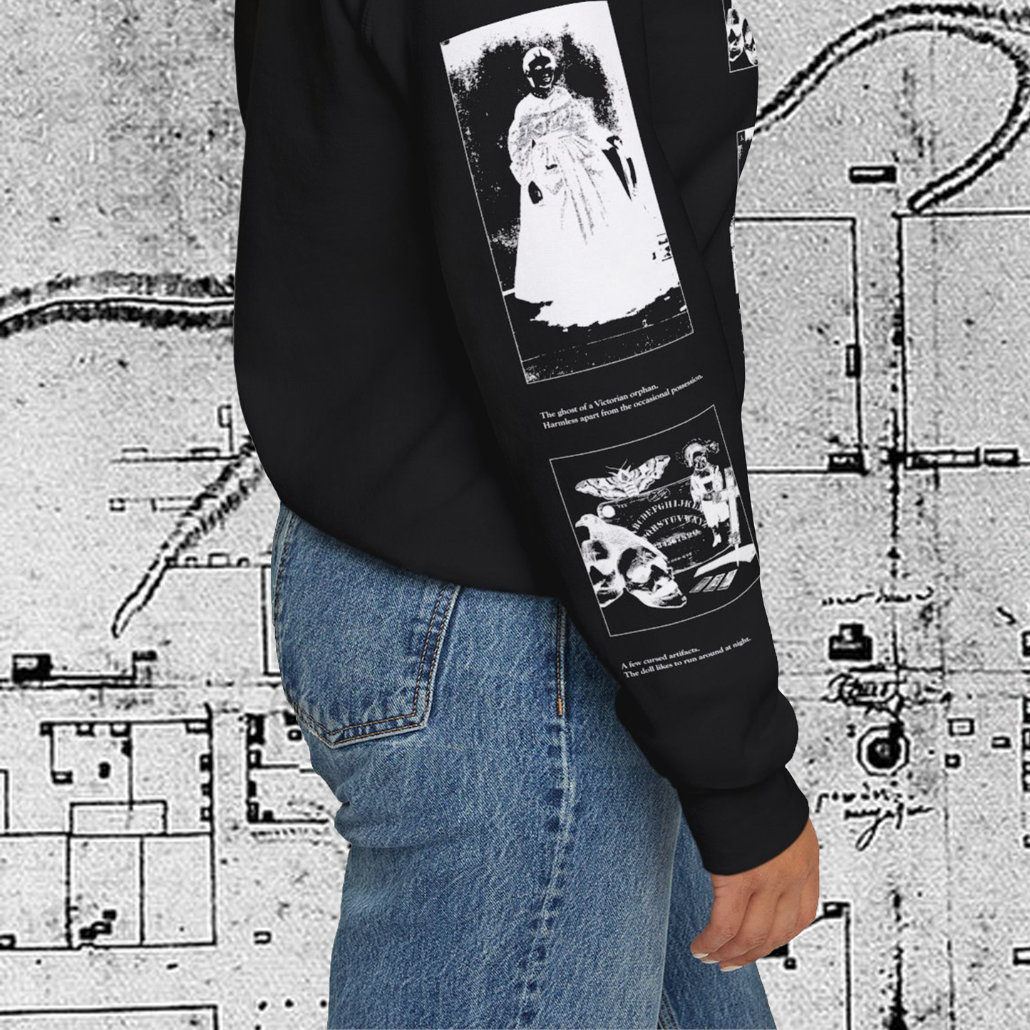 Grant Us Night Horror House black sweatshirt sleeve with white graphic design text and a haunted house with ghosts and footprints and cursed objects and illustrations on a textured background