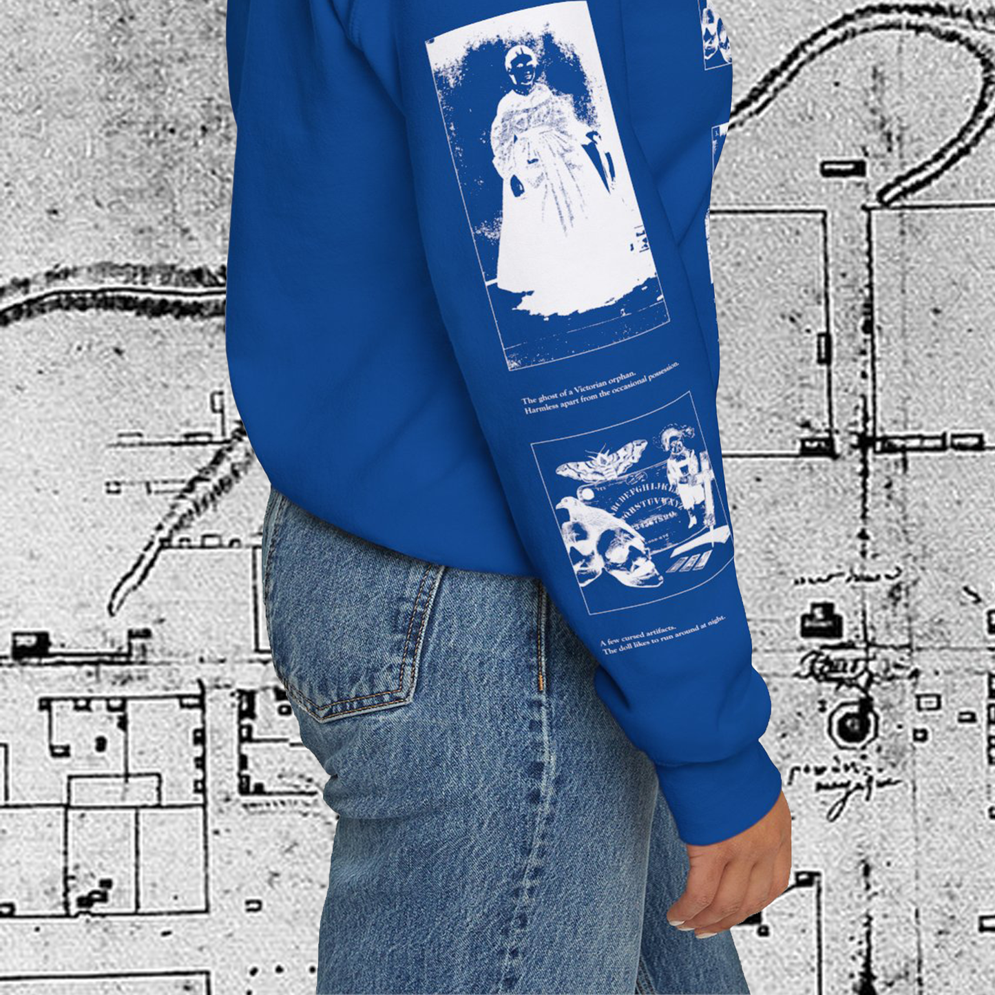 Grant Us Night Horror House blue sweatshirt sleeve with white graphic design text and a haunted house with ghosts and footprints and cursed objects and illustrations on a textured background