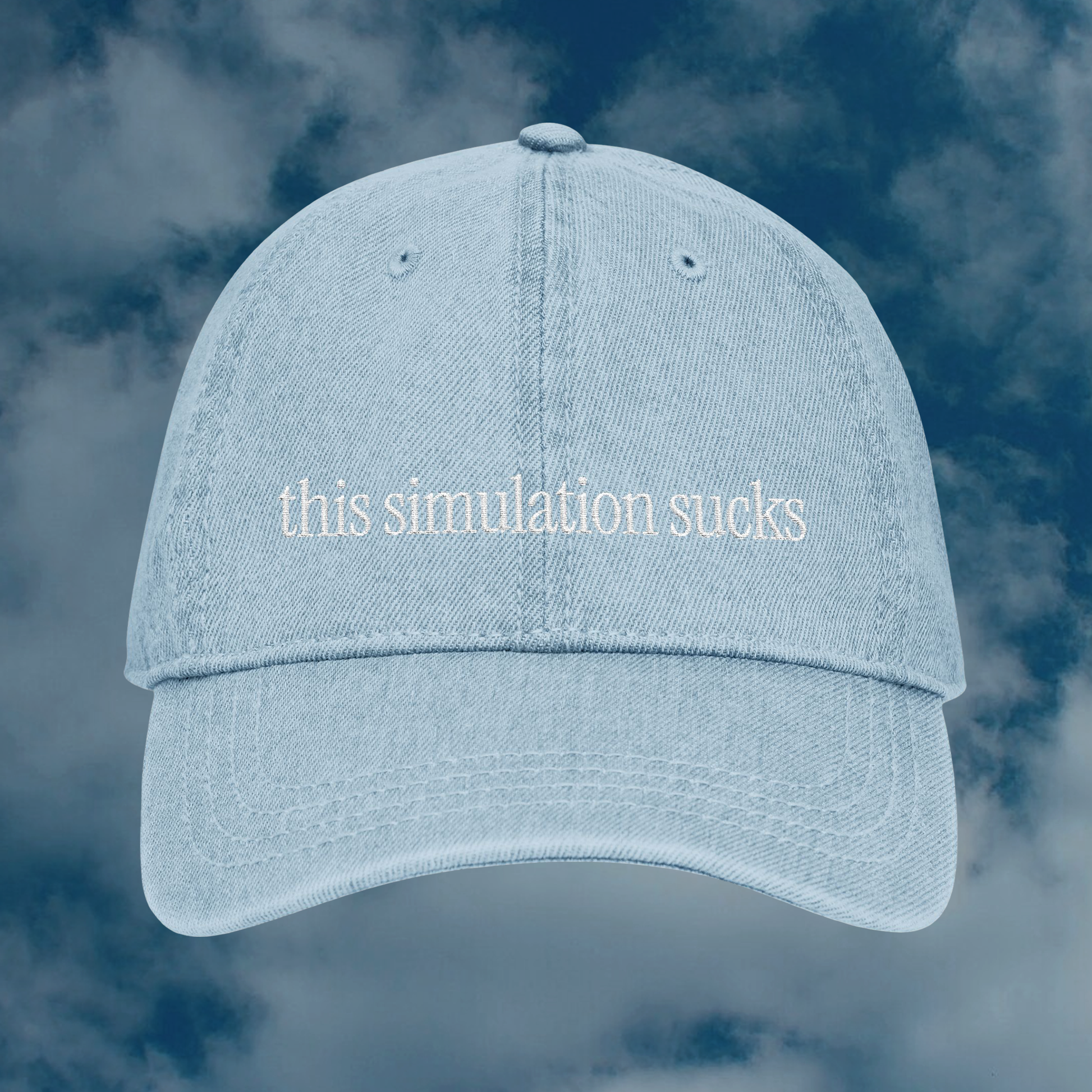 Grant Us Night Simulation light blue denim cap with 'this simulation sucks' white text embroidered against a blue sky background