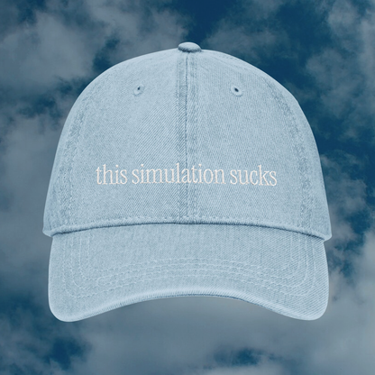 Grant Us Night Simulation light blue denim cap with 'this simulation sucks' white text embroidered against a blue sky background